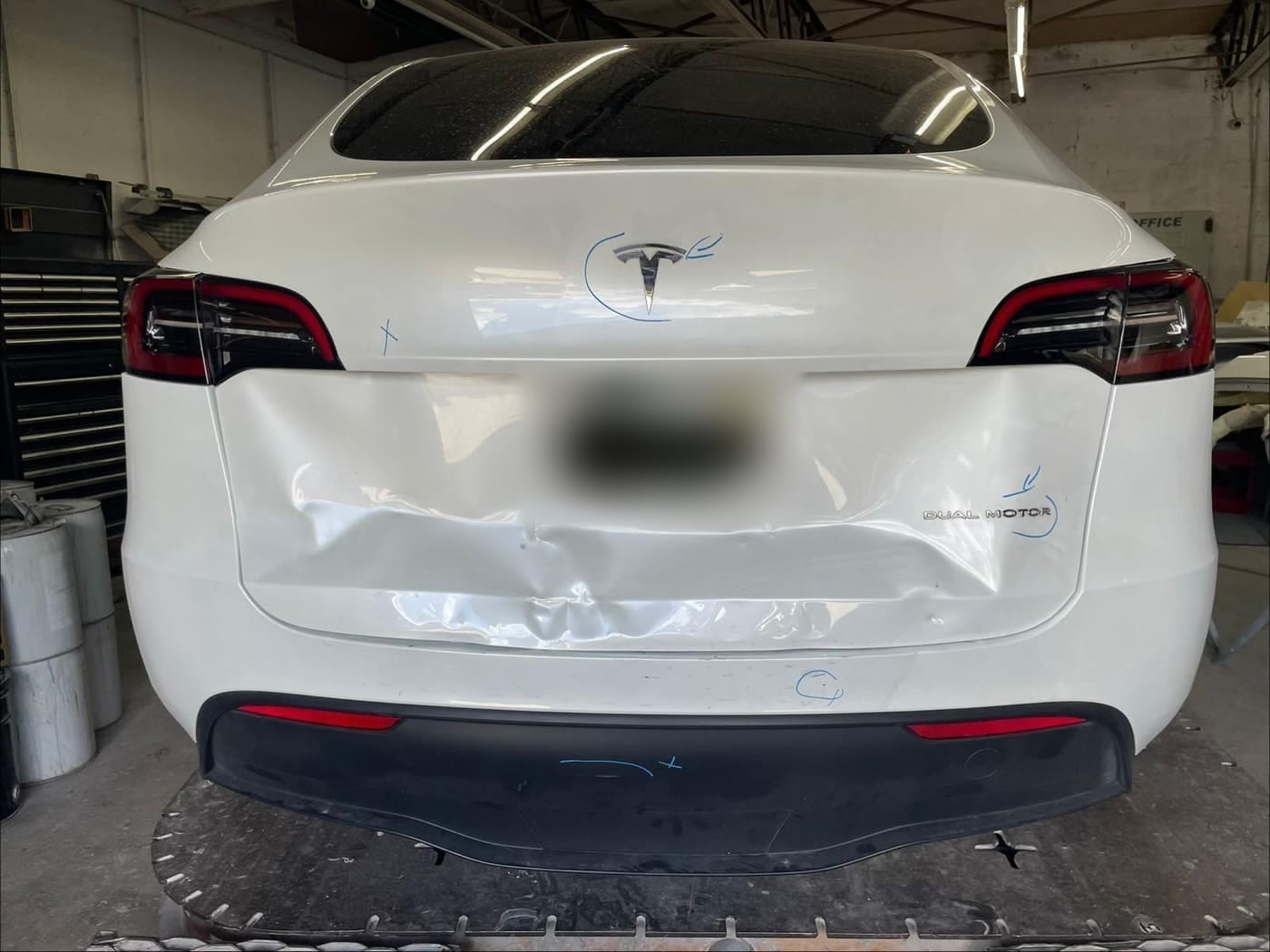 The same white Tesla before repair, showing collision damage